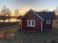 Röd liten stuga i Småland, vackert belägen vid badsjö