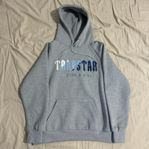 Grå hoodie från Trapstar med blå märke.