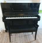 Äldre svart piano med pall finns på bottenvåning avhämtn