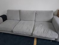 En grå soffa med tre sittplatser. Måtten är : 250 cm x90 