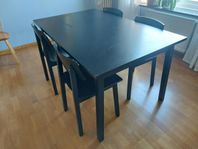 Svart matsalsmöbel med iläggsskiva och fyra stolar