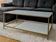 Modernt soffbord med glas och guldfärgat underrede