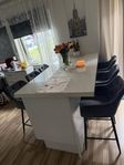 En köksö med plats inuti och 6 barstolar 