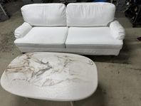 en vit, fin soffa tillsammans med ett soffbord i marmor 