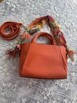 Chic Orange Handbag with Floral Scarf and Strap
