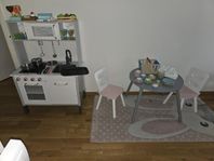 Barnkök med tillbehör och bord och stolar och matta