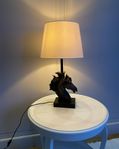 Svart bordslampa i form av ett hästhuvud med fin lampskärm