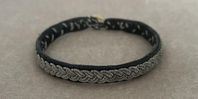 Svart läderarmband med flätad design av tenn