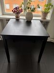 Fin välbevarade byrå , litet köksbord med två stolar .