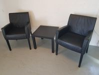 2 st svarta skinnfåtöljer med litet bord.