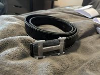svart bälte med silvrig logga