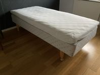 90-säng. Resår- och bäddmadrass. Fina snidade sängben 