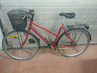 Damcykel i rött med stor svart cykelkorg och pakethållare